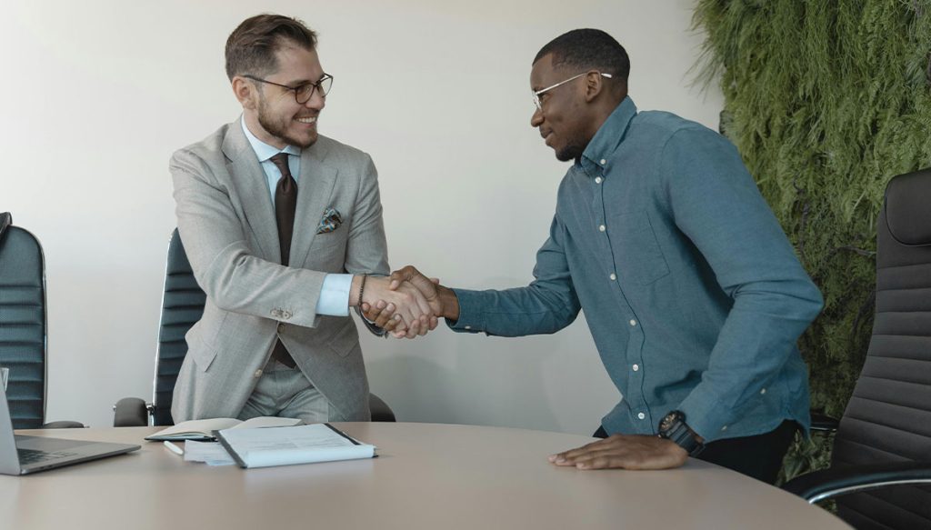 two men shaking hands in an office boardroom